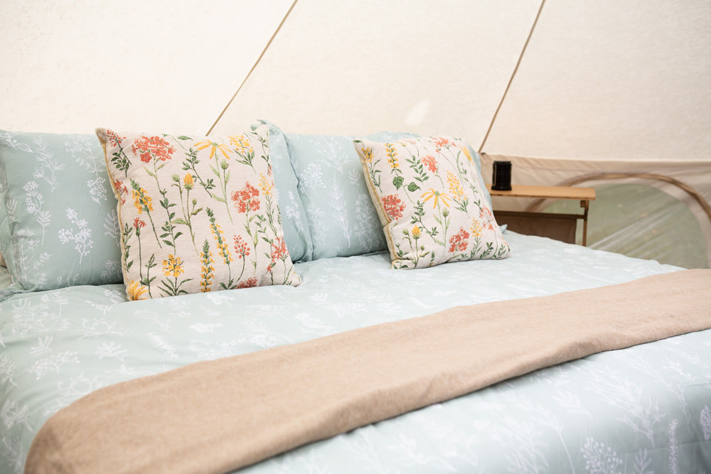 Comfortable bed and linens in glamping tents